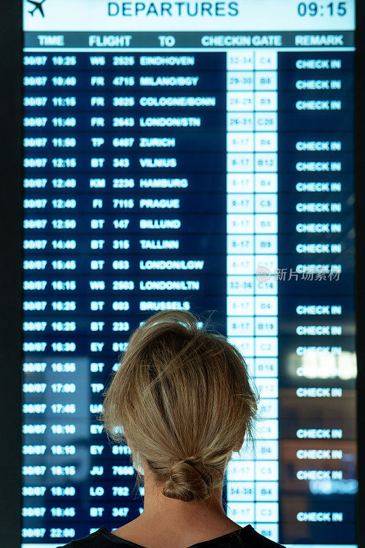 Woman looking on the display with information about a flights in